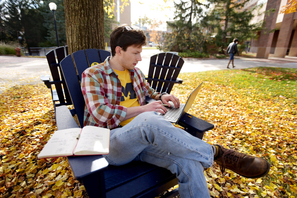 A student sitting in a chair studying outside