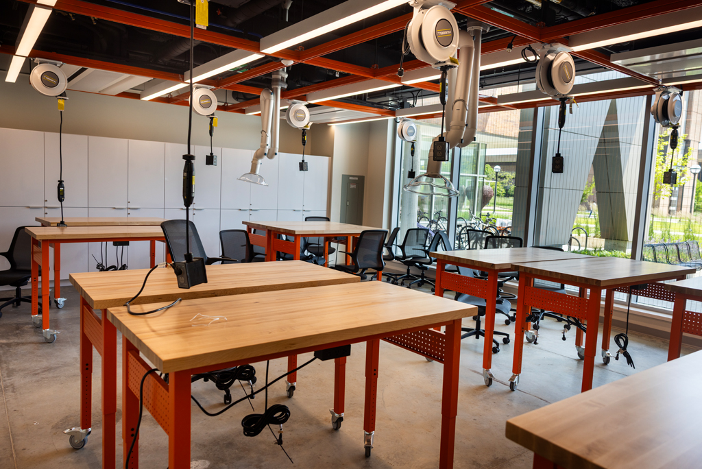 An industrial looking room with workbenches and overhead electrical drops