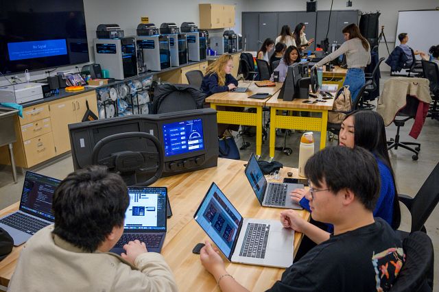 A group of students on laptops in a maker lab.