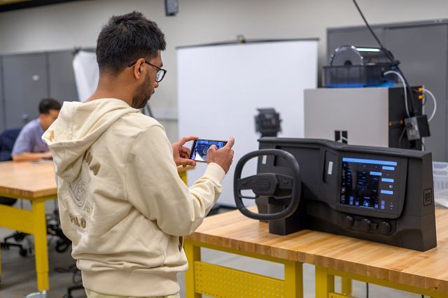 A student taking a picture of a 3D printed car dashboard
